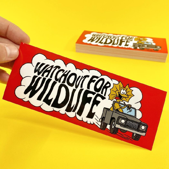 Red sticker with 'Watch Out for Wildlife' text and cartoon character on a yellow background