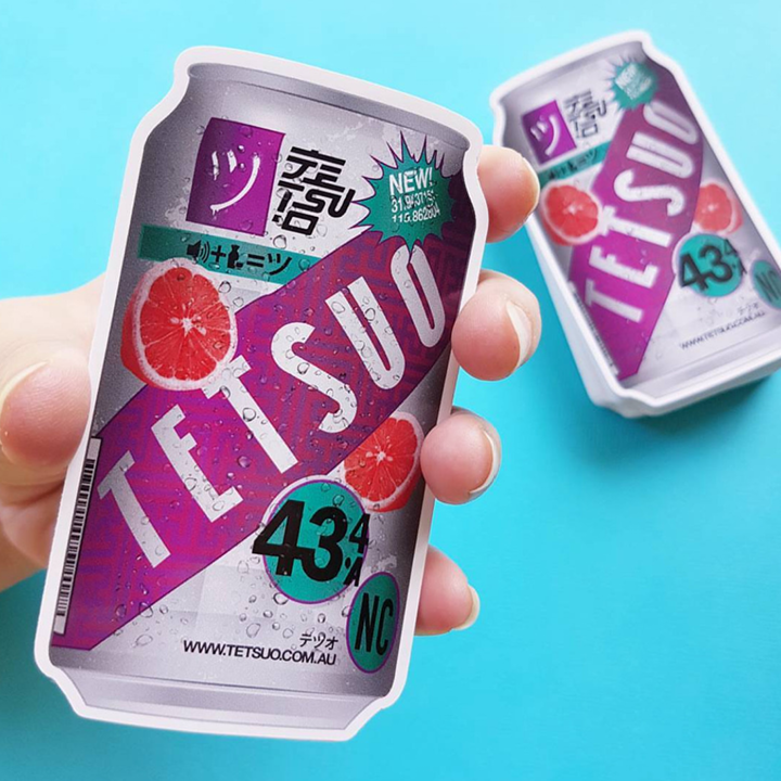 Die-cut stickers with hand holding a Tetsuo can against a blue background