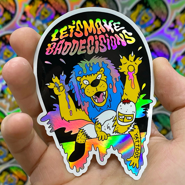 Holographic sticker with colorful design of two lions and text 'Let's Make Bad Decisions' held by a hand.