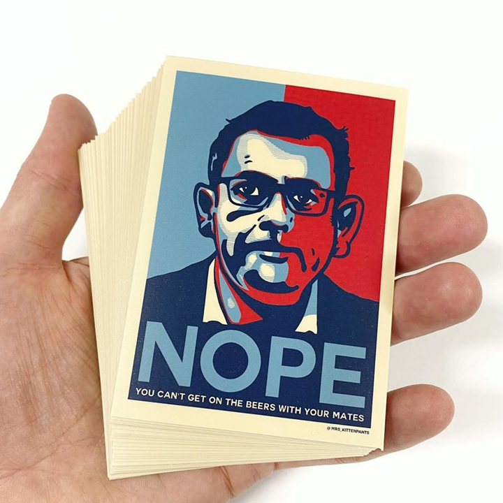 Hand holding a stack of stickers with a design featuring a face and the word 'NOPE' on a white background.