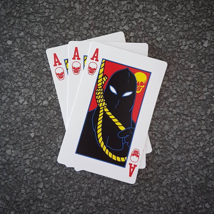 Three playing card stickers with a unique design on a textured surface