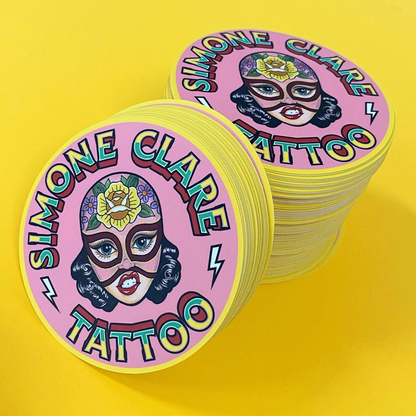 Stack of pink stickers with 'Simone Clare Tattoo' branding on a yellow background