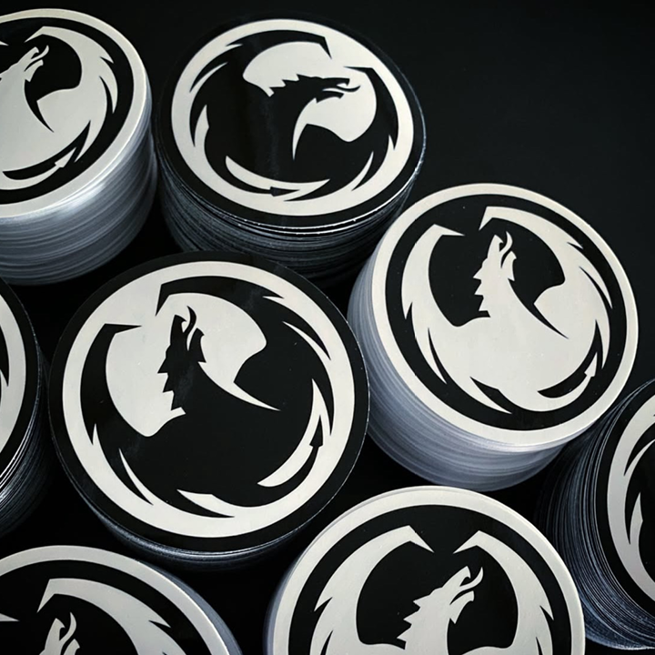 Stacks of stickers with the dragon logo on a dark background