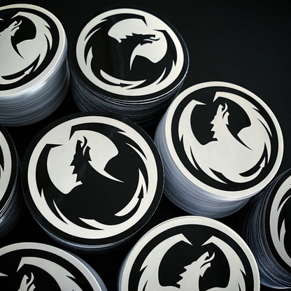 Stacks of stickers with the dragon logo on a dark background