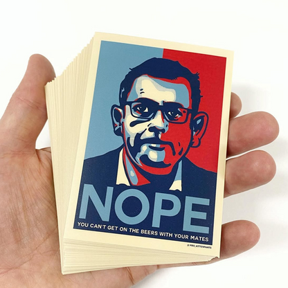 Hand holding a stack of stickers with a design featuring a face and the word 'NOPE' on a white background.